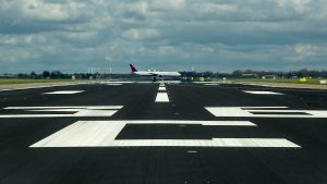 Airport runway maintenance operations with aircraft taxiing at Schiphol Airport.